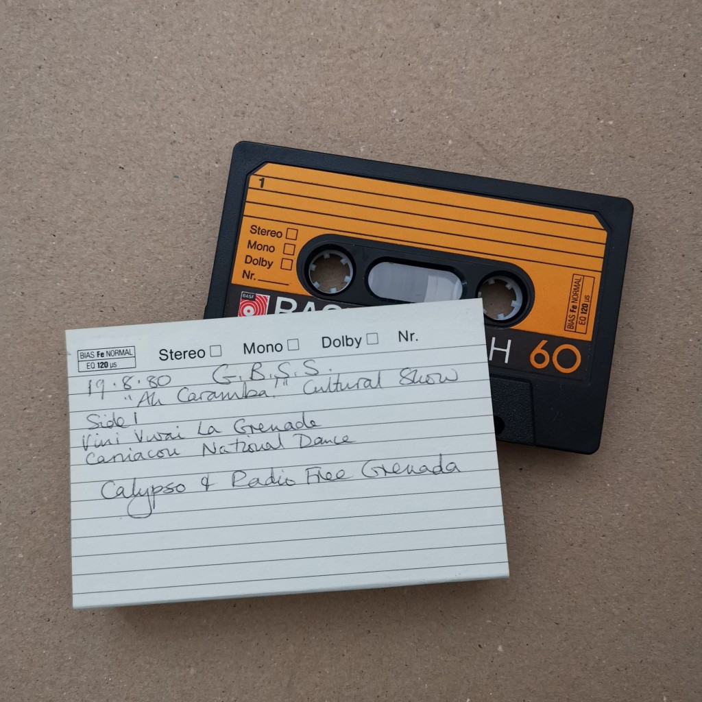 Photograph of cassette tape with card insert, containing handwritten information about the contents of the tape. 